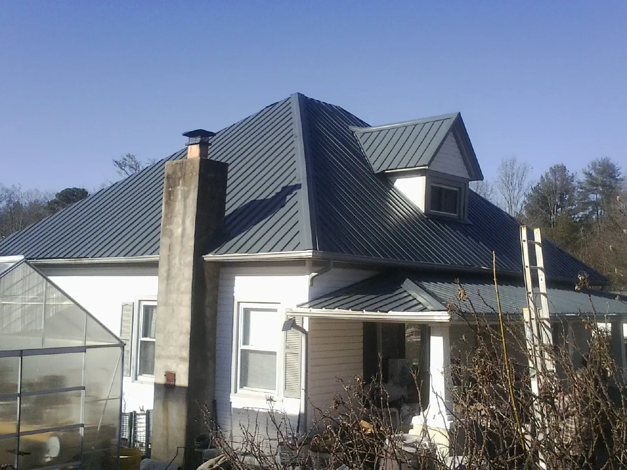 Dark blue standing seam metal roof on a white farmhouse with dormer — Slate & Tile Roof Repair by Roofing Brothers in Nazareth