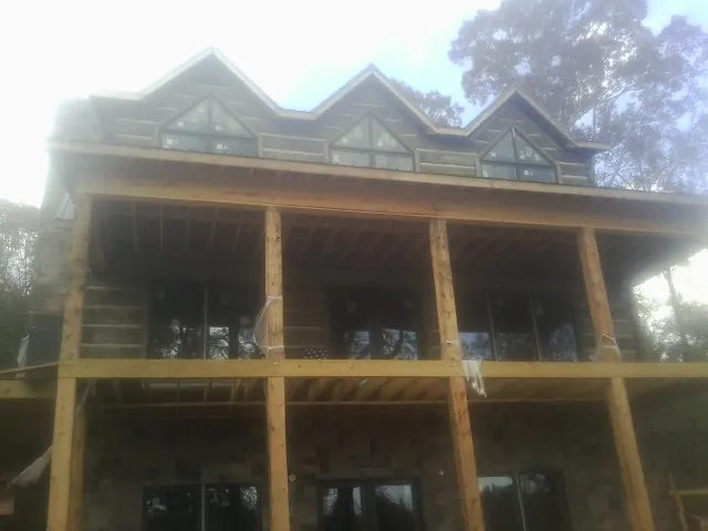 Dormers and porch framing on a large log home under construction — Roof Coating work by our crew in Nazareth