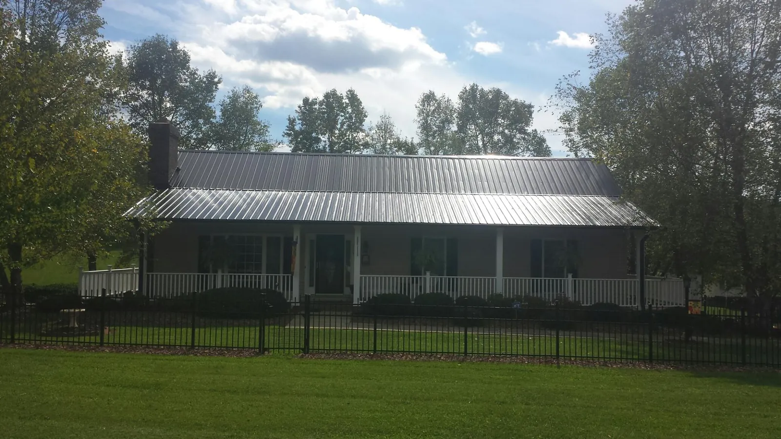 Gray metal roof on a brick ranch with a full width front porch — Gutter Guard Installation work by our crew in Nazareth