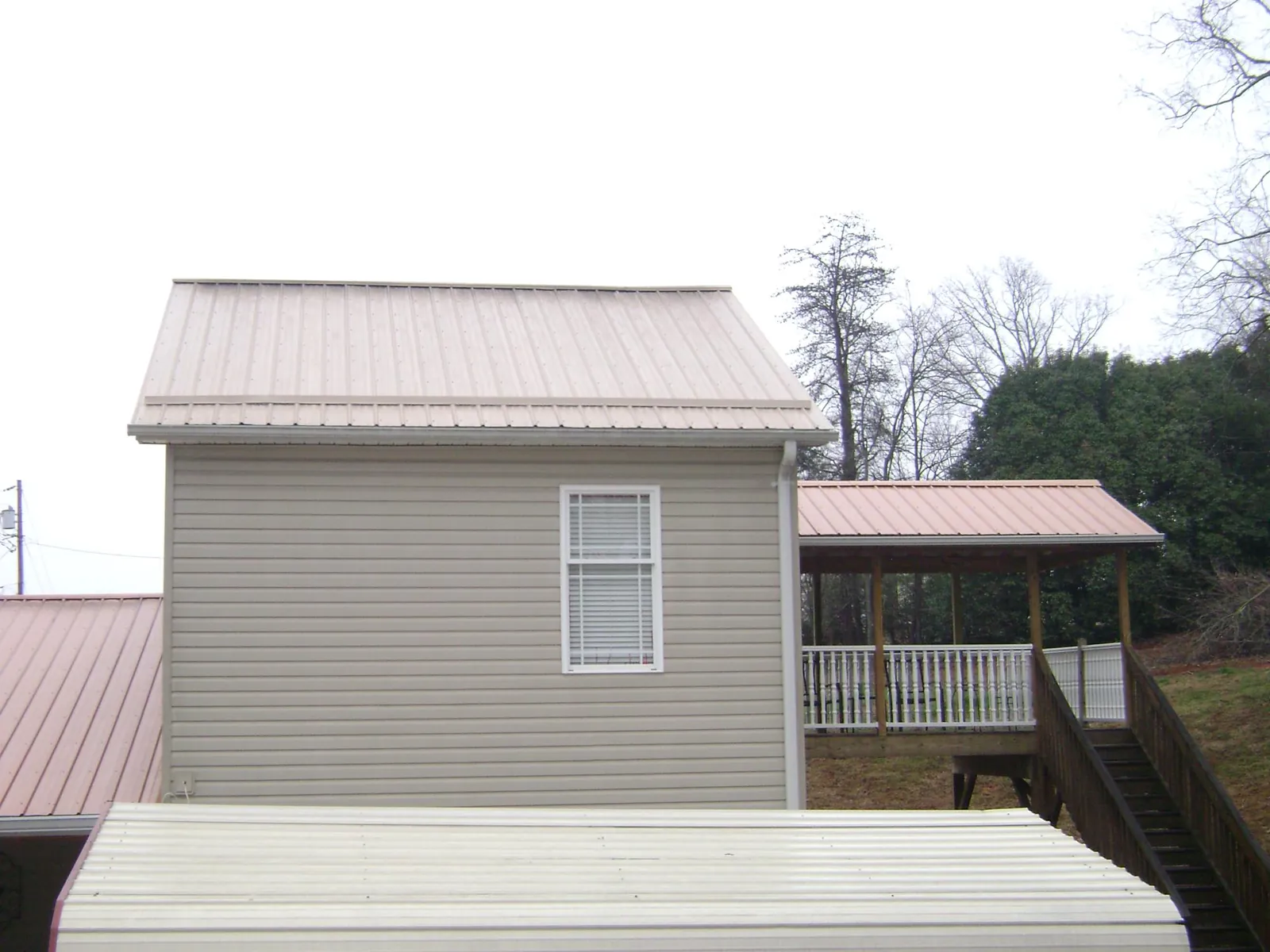 Tan metal roofs on a two story addition and attached porch, from a Roof Replacement job in Nazareth