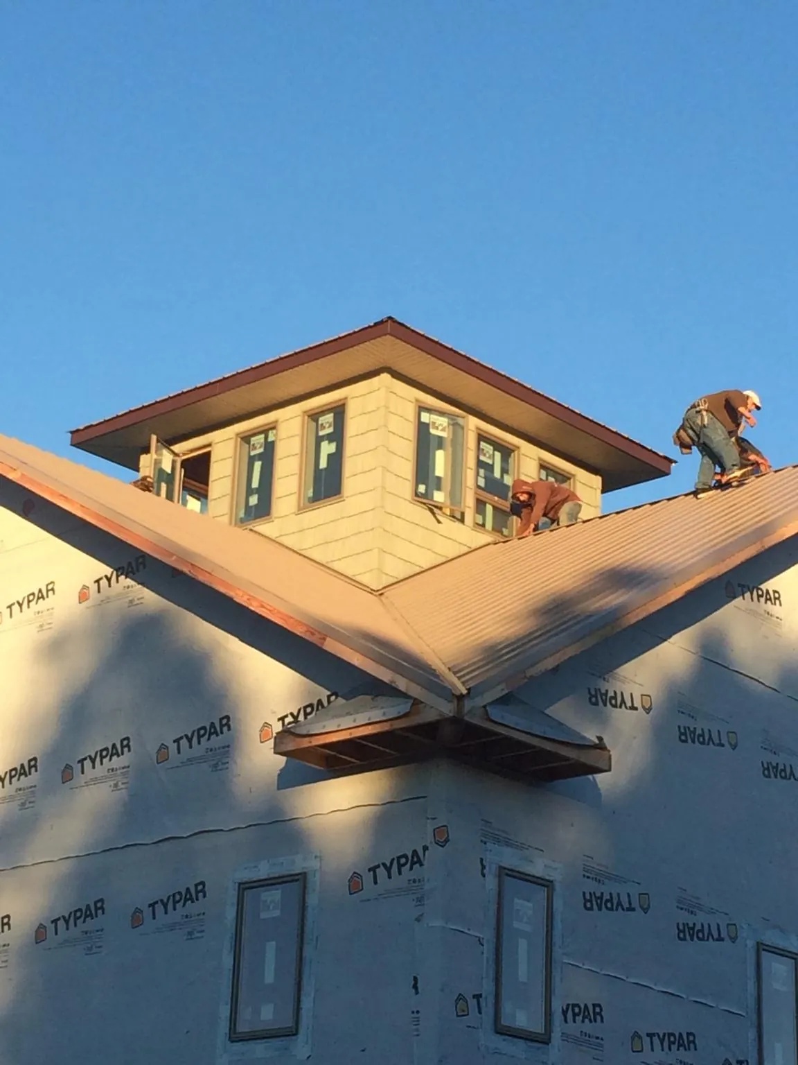 Roofers working around a rooftop cupola on a new metal roof at sunset — Roof Waterproofing in Nazareth by Roofing Brothers